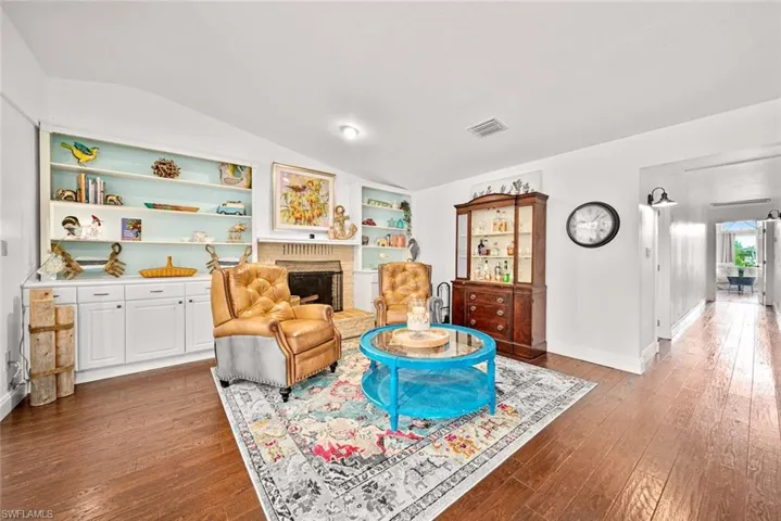 Living room with a fireplace, hardwood / wood-style flooring, built in shelves, and lofted ceiling