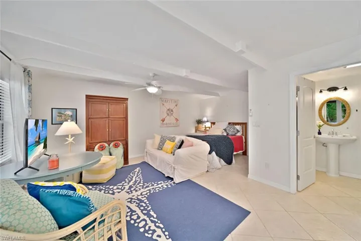 Tiled bedroom with sink, ceiling fan, and ensuite bathroom