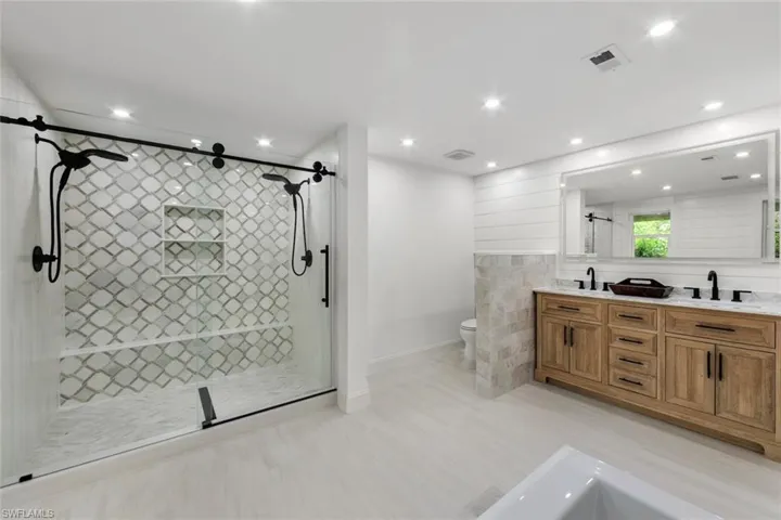 Bathroom with toilet, an enclosed shower, and vanity