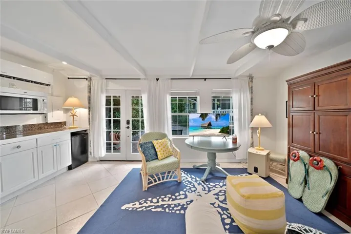 Sitting room featuring a wall mounted AC, french doors, light tile patterned floors, and ceiling fan