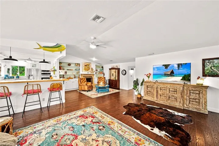 Living room featuring ceiling fan, vaulted ceiling, and dark hardwood / wood-style floors