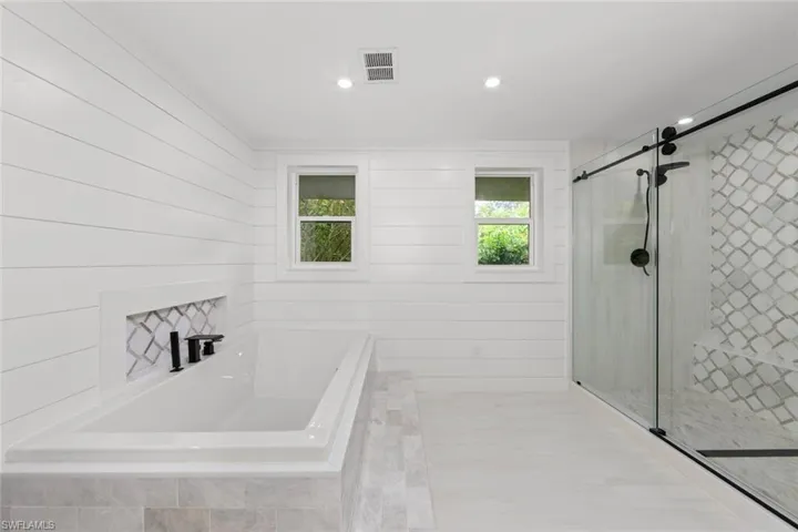 Bathroom featuring a wealth of natural light and separate shower and tub