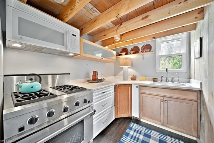 Kitchen featuring wooden ceiling, beamed ceiling, sink, high end range, and dark hardwood / wood-style flooring