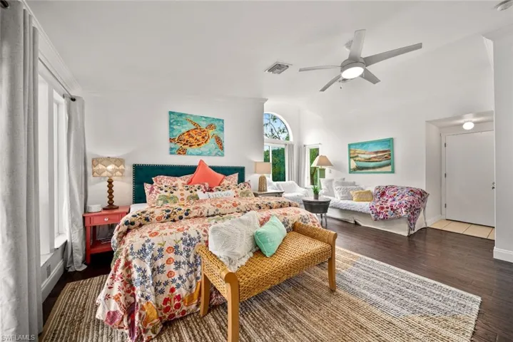 Bedroom featuring ceiling fan, wood-type flooring, and vaulted ceiling