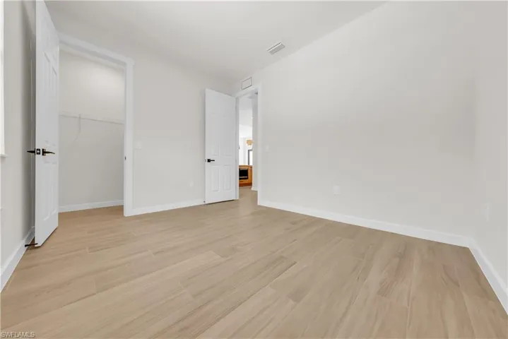 Unfurnished bedroom with light wood finished floors and a spacious closet