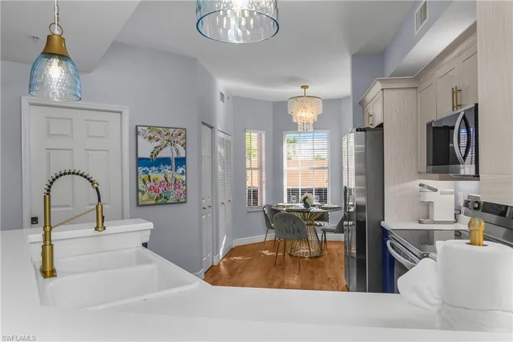Kitchen with stainless steel appliances, pendant lighting, light wood finished floors, and a chandelier