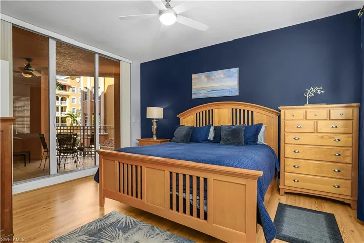 Bedroom featuring wood finished floors, a wall of windows, access to outside, ceiling fan, and an accent wall