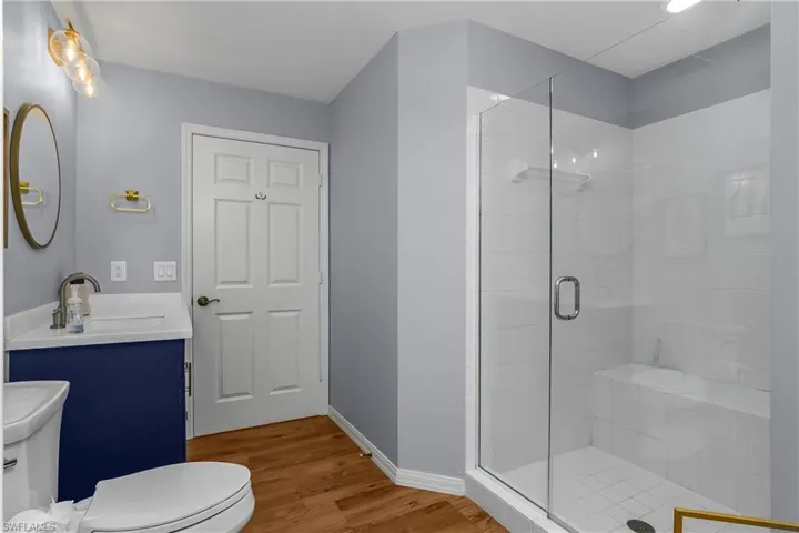 Full bath with vanity, a shower stall, and light wood finished floors