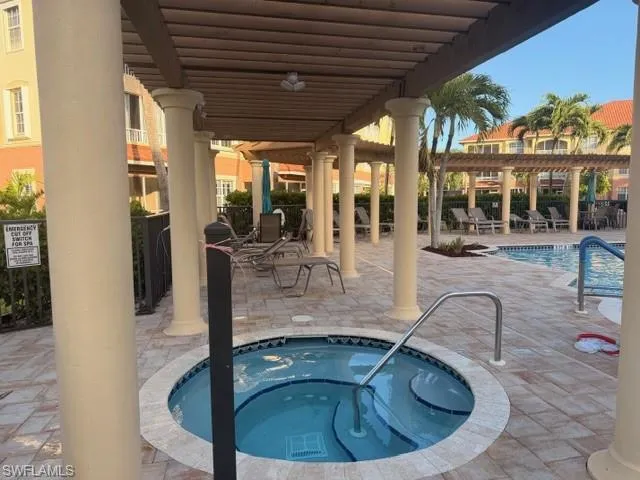 Sparkling community pool with paver patio, pergola shade structure, and relaxing community hot tub spa