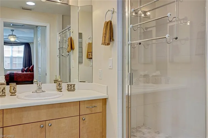 Private ensuite bathroom with dual vanity, walk-in shower stall, and ceiling fan