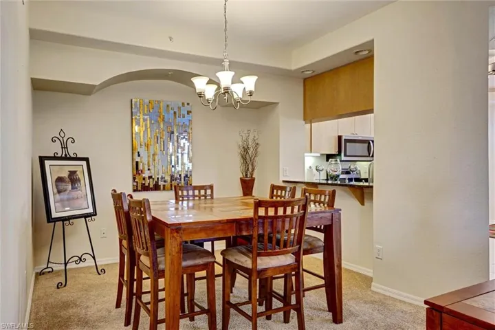 Carpeted dining area bathed in natural light with an elegant chandelier — perfect for entertaining