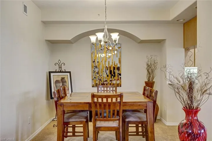 Formal dining room with plush carpet, designer pendant lighting, and beautiful arched walkways