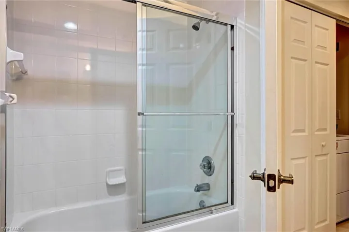 Bathroom with closet, glass-door shower/tub combo, and in-unit washer and dryer