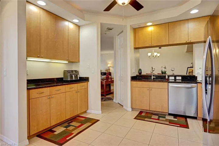 Chef-friendly kitchen featuring stainless steel appliances, dark stone counters, ceiling fan, and contemporary pendant lighting