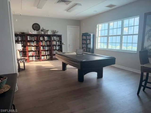 Community recreation room with billiards/pool table and hardwood-style floors — great amenity for residents