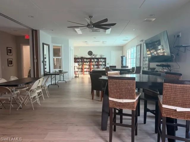 Community dining or clubhouse room with ceiling fan and wood-style flooring
