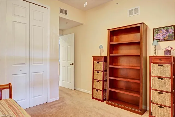 Guest bedroom with light carpet and built-in closet