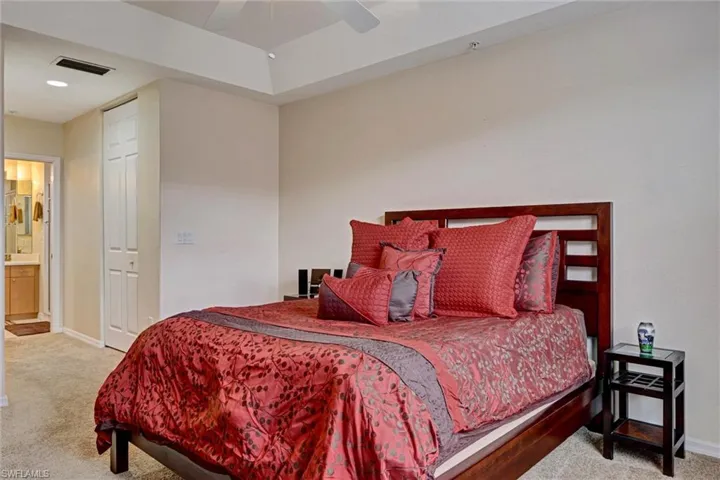 Primary bedroom with plush carpet, ceiling fan, and convenient ensuite bathroom