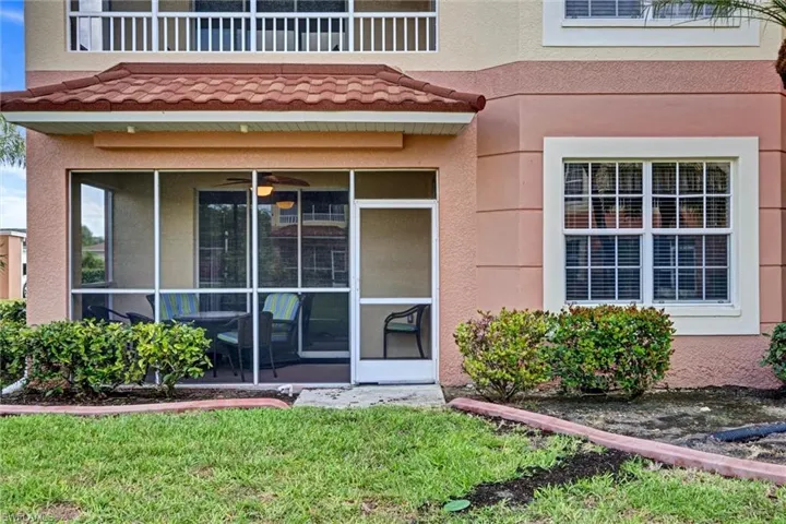 Condo entry with screened lanai, stucco exterior, and landscaped lawn