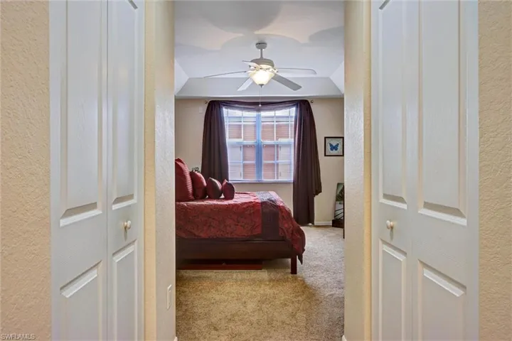 Comfortable guest bedroom with plush carpet, textured accent wall, and ceiling fan