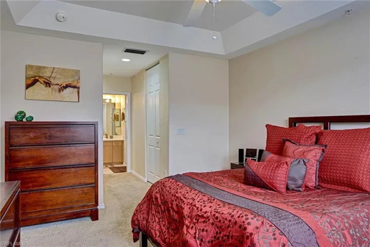 Generously sized primary bedroom with walk-in closet, plush carpet, ceiling fan, and private ensuite bathroom