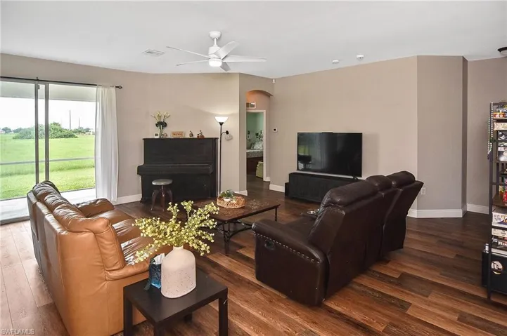 Living area featuring arched walkways, dark wood-style flooring, and ceiling fan