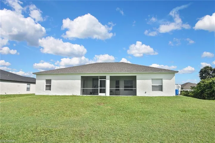 Back of house with a lawn, a sunroom, and stucco siding