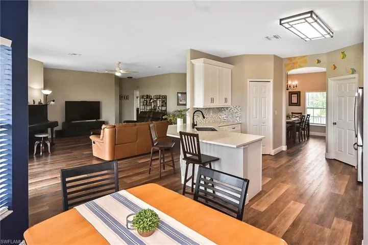 Dining area featuring a ceiling fan, dark wood-style flooring, arched walkways, and a chandelier