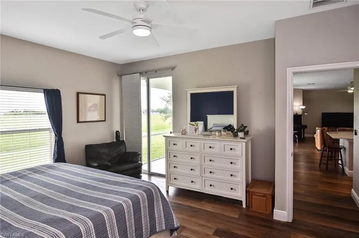 Bedroom with dark wood finished floors, multiple windows, access to outside, and a ceiling fan
