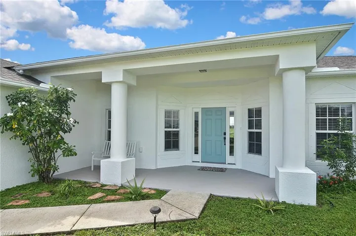 View of exterior entry with a porch, stucco siding, and a shingled roof