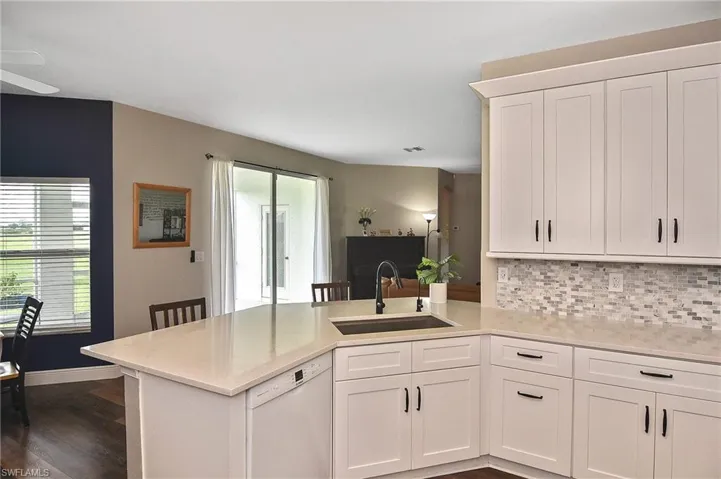 Kitchen featuring white cabinets, white dishwasher, a peninsula, and tasteful backsplash