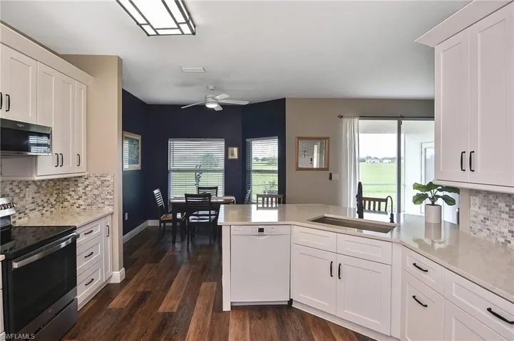 Kitchen with tasteful backsplash, stainless steel appliances, white cabinets, ceiling fan, and a peninsula