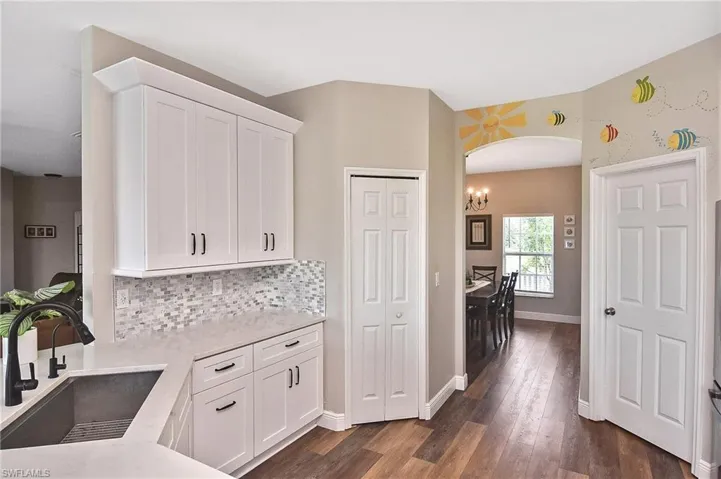 Kitchen with white cabinetry, arched walkways, light stone countertops, and tasteful backsplash