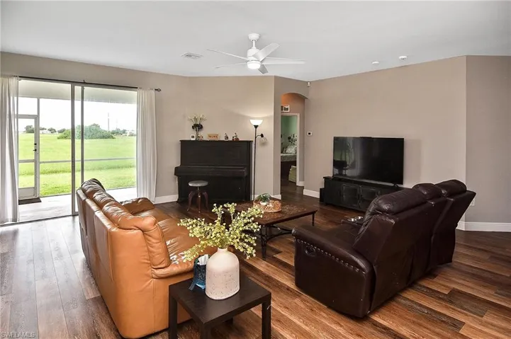 Living area featuring arched walkways, wood finished floors, and ceiling fan