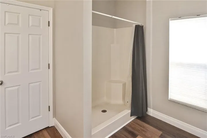 Full bathroom with a stall shower and dark wood finished floors