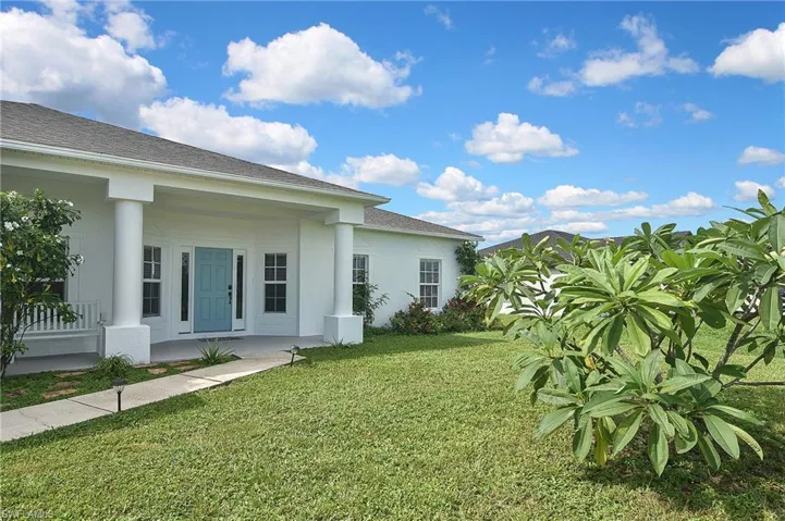 View of green lawn featuring covered porch