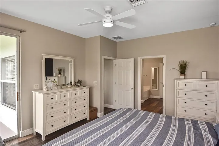 Bedroom with connected bathroom, ceiling fan, and dark wood-type flooring
