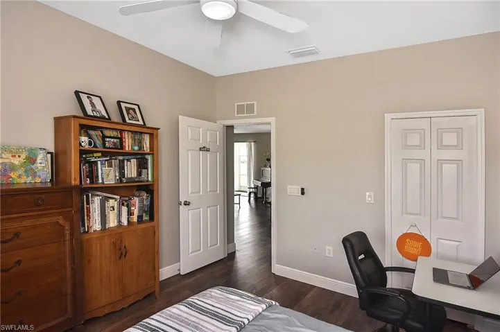 Bedroom with a desk, dark wood-style flooring, and ceiling fan