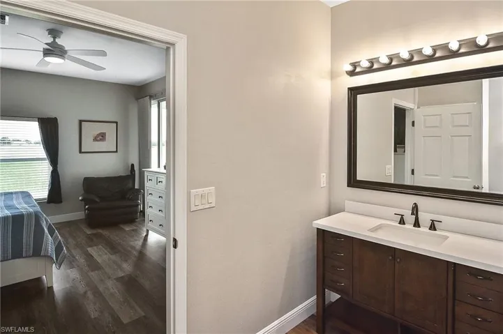 Bathroom with vanity, dark wood-type flooring, a ceiling fan, and ensuite bathroom