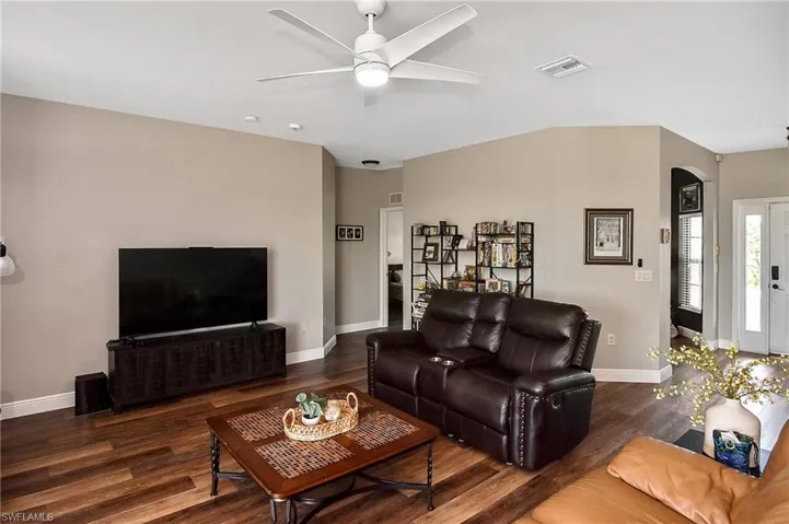 Living area with dark wood finished floors, a ceiling fan, and arched walkways