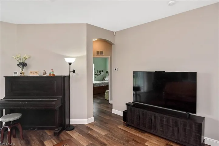 Living area with arched walkways and dark wood-style floors