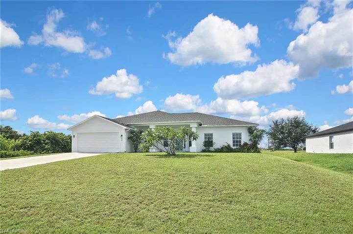 Ranch-style house with a front yard, driveway, stucco siding, and an attached garage