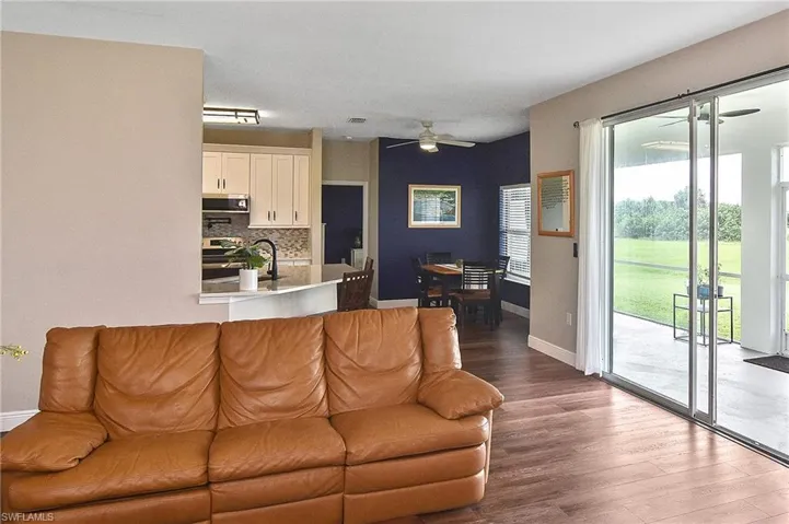 Living room with a ceiling fan and dark wood-style flooring