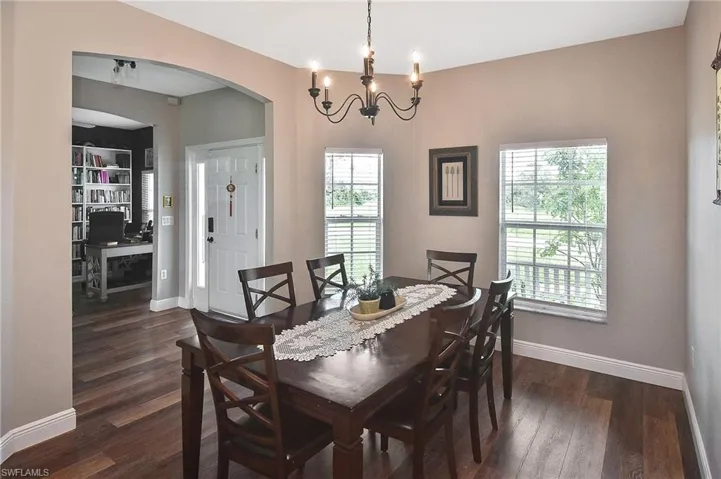 Dining area with arched walkways, dark wood finished floors, a chandelier, and an office area