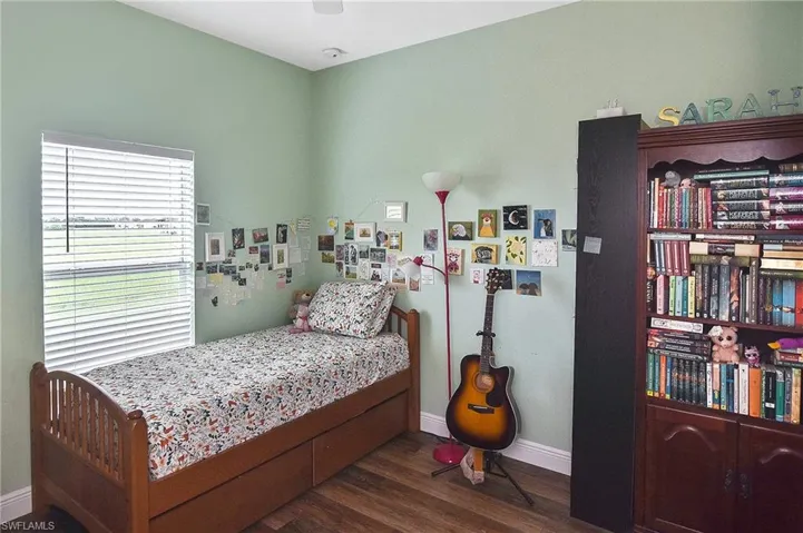 Bedroom featuring dark wood-style floors and baseboards