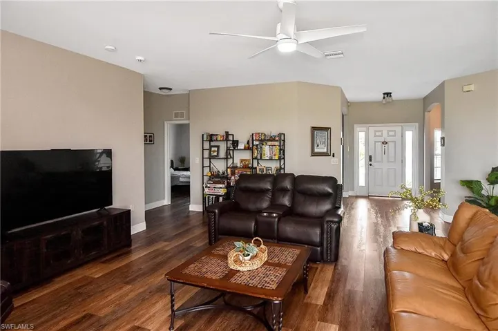 Living room with dark wood-style floors and a ceiling fan