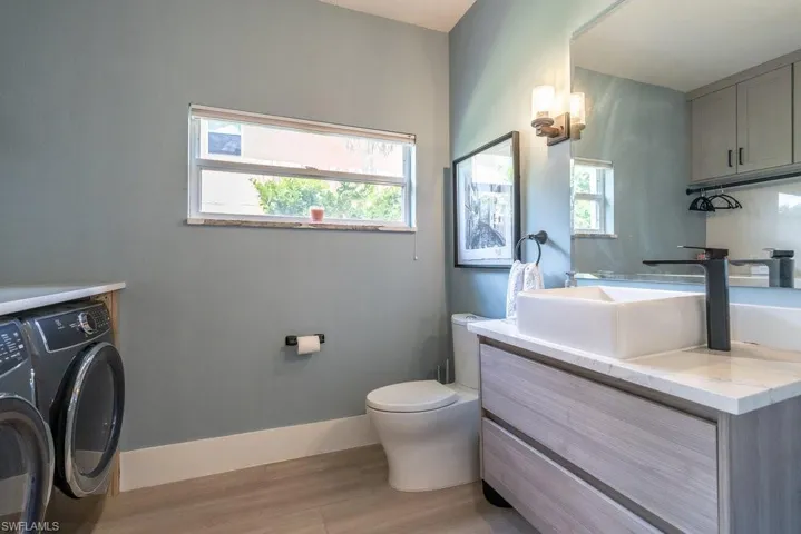 Bathroom with washer and dryer, vanity, and wood finished floors