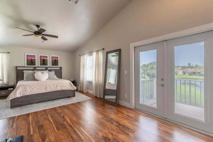 Bedroom featuring vaulted ceiling, access to exterior, wood finished floors, and ceiling fan