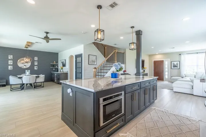 Kitchen featuring open floor plan, light wood-style flooring, light stone counters, decorative light fixtures, and recessed lighting