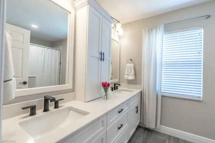 Bathroom featuring double vanity, wood finished floors, and recessed lighting